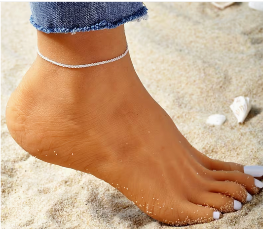 Silver minimalist chain anklet worn on the ankle at the beach with a delicate, simple design