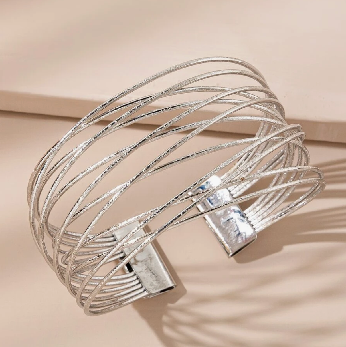 Silver bracelet with multiple loops on a beige background