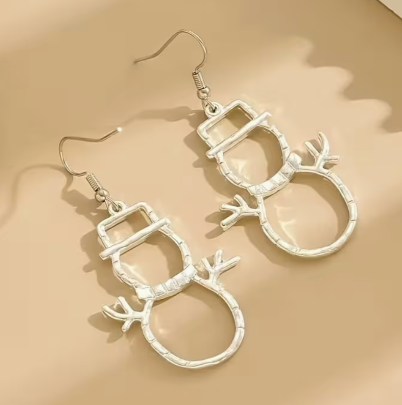 Silver snowman-shaped earrings on a beige background