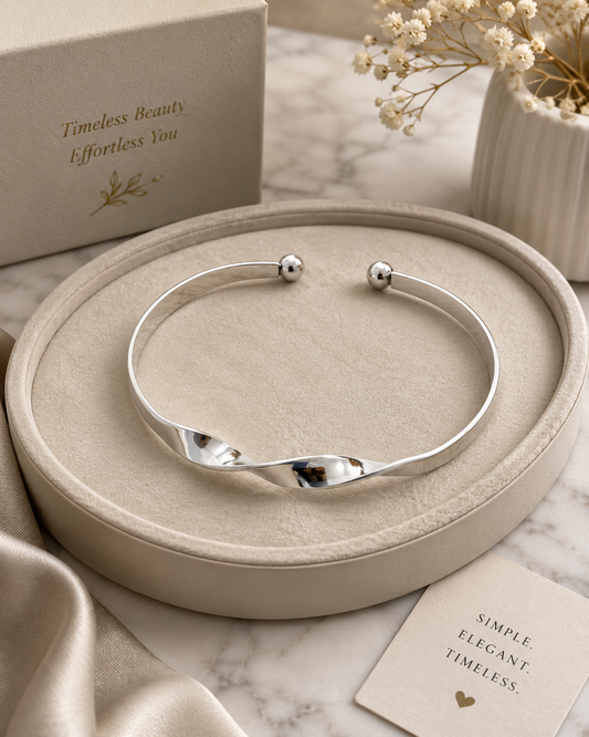 Elegant silver-tone adjustable cuff bracelet featuring a modern wave design and polished ball ends displayed on a jewelry tray.