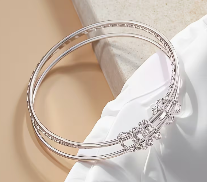 Silver-tone adjustable cuff bracelet featuring a wrapped wire accent and textured band design.