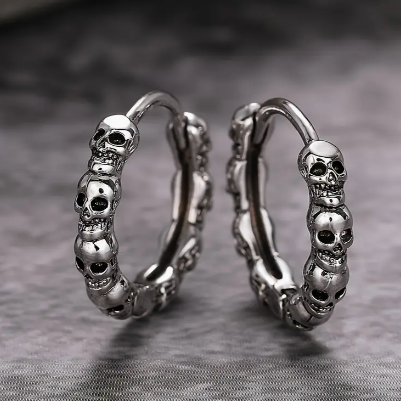 Silver skull hoop earrings on a gray background