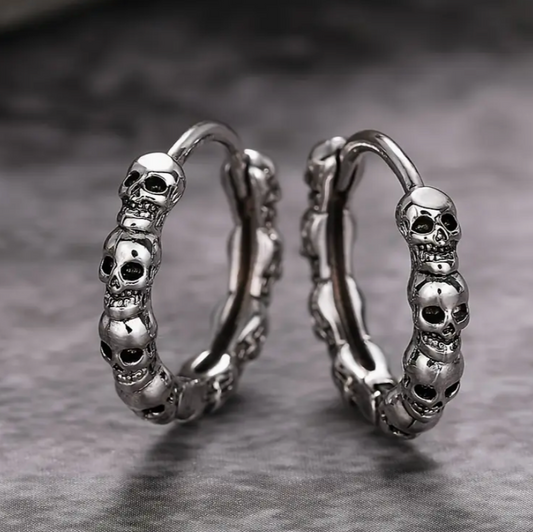 Silver skull hoop earrings on a gray background