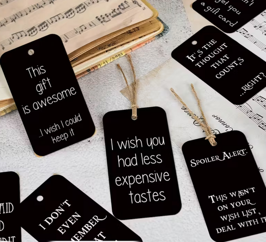 several snarky gift tags styled on desk with vintage sheet music