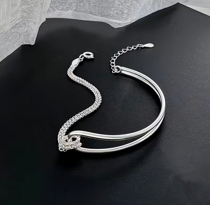 Silver-tone spliced knot double layer bracelet featuring a sleek curved bar design and adjustable chain closure.