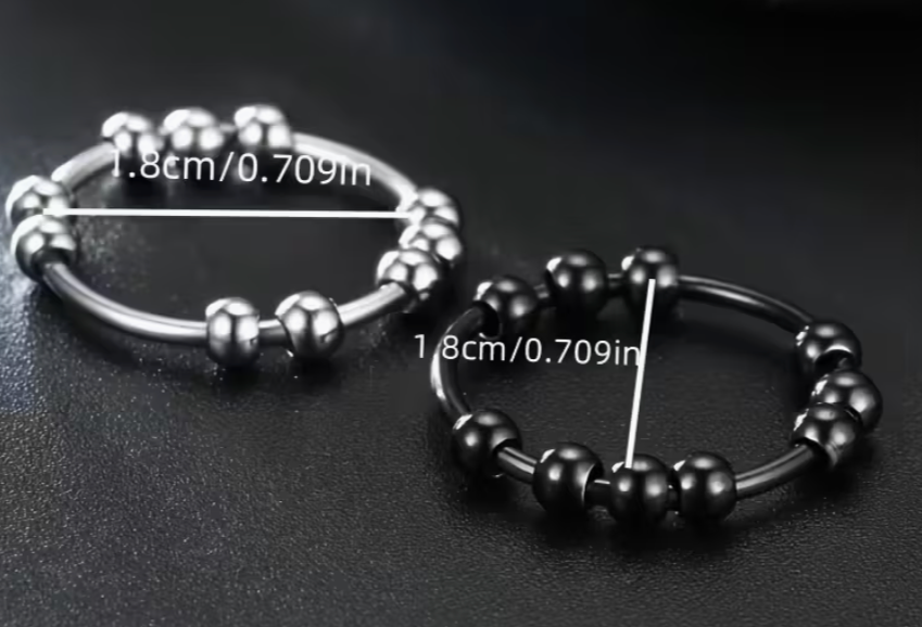 Two stainless steel beaded spinner fidget rings in silver and black showing rotating beads and size measurement of 1.8 cm diameter on a dark background