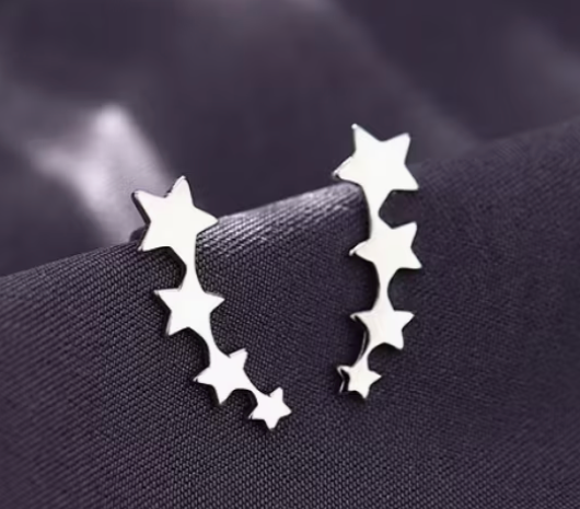 Silver-tone stainless steel star climber earrings with cascading star design displayed on dark fabric