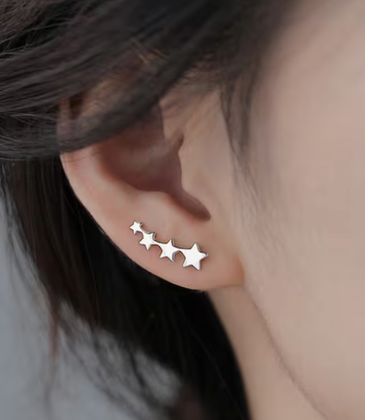 Woman wearing minimalist stainless steel star climber earrings with celestial ear crawler design