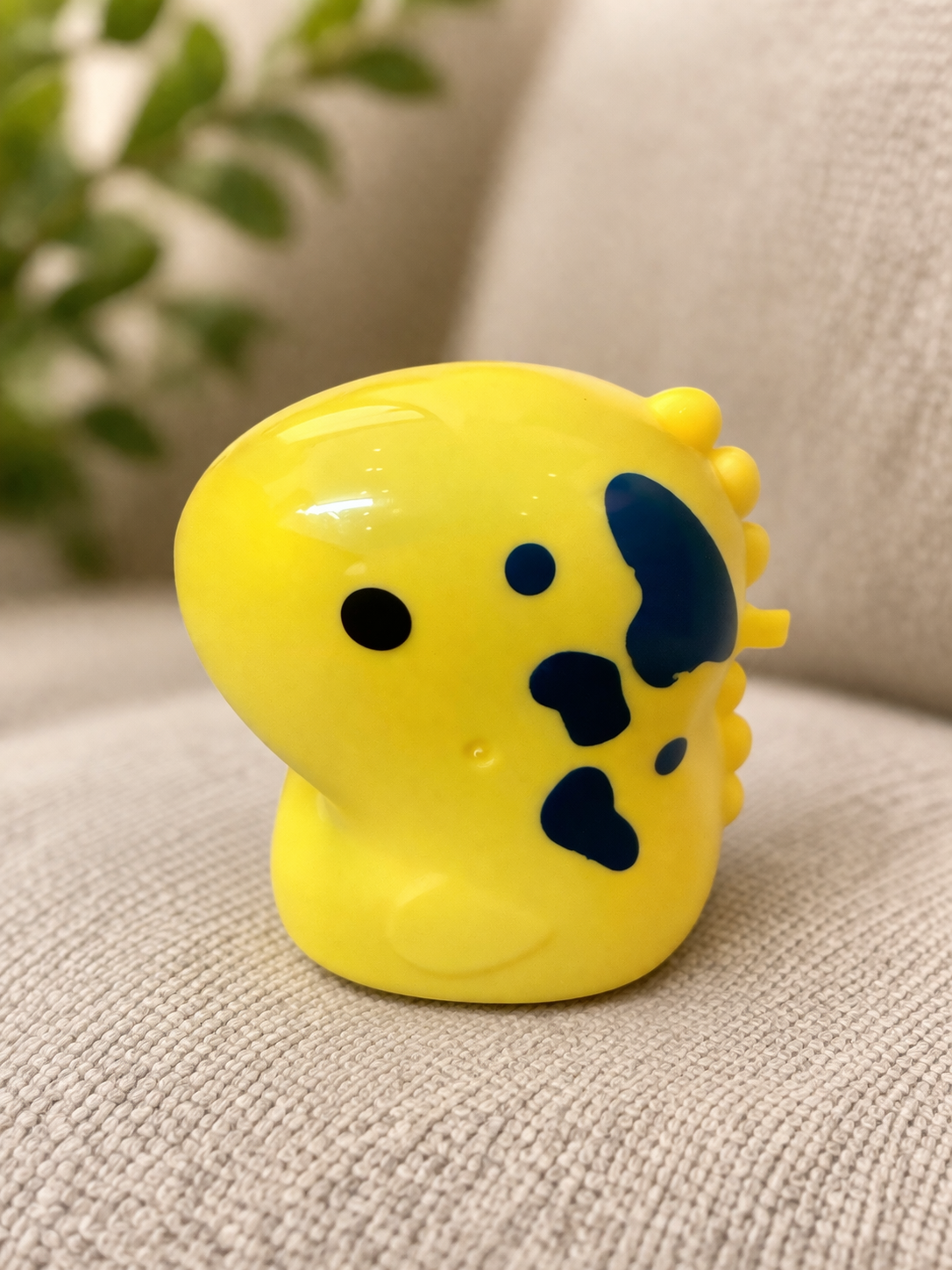 Yellow toy with black spots on a textured surface