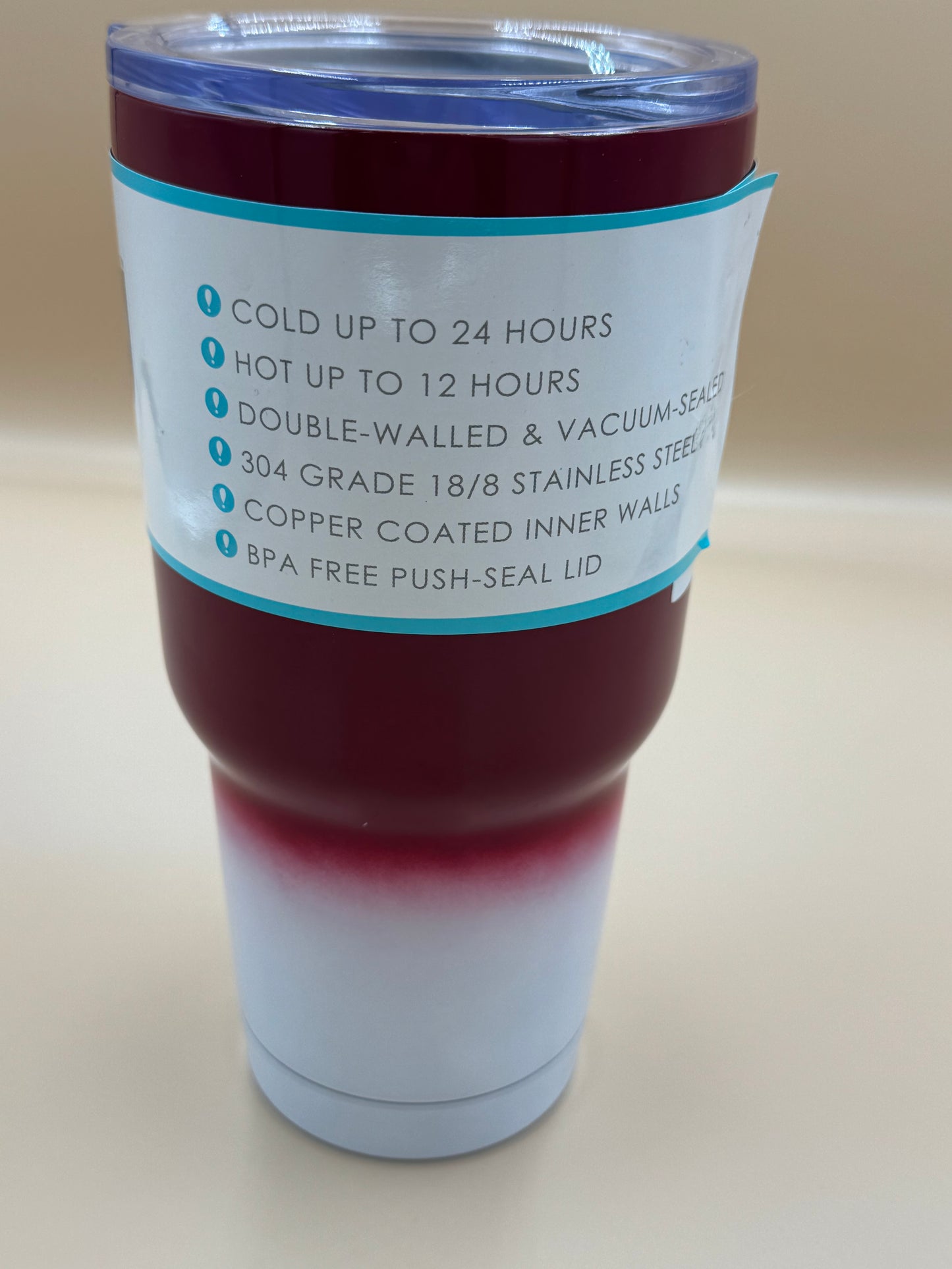 Stainless steel tumbler with red liquid and text on a beige background