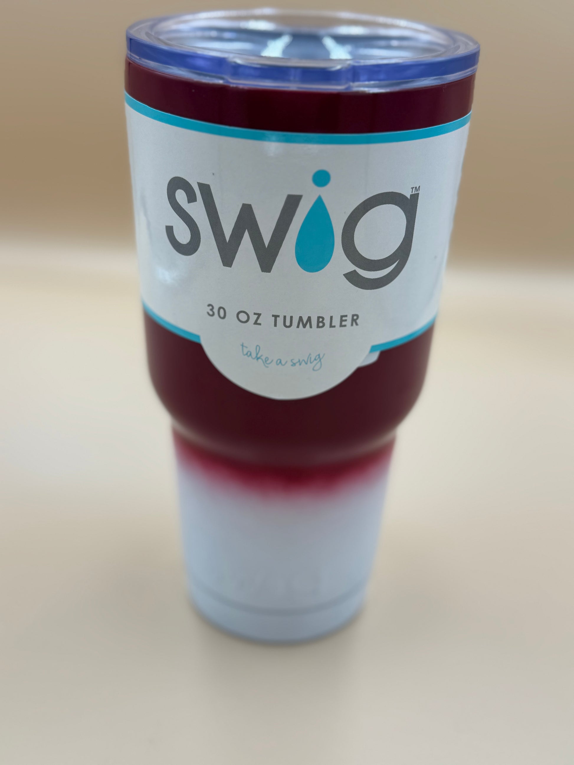 Swig tumbler with a red interior on a beige background