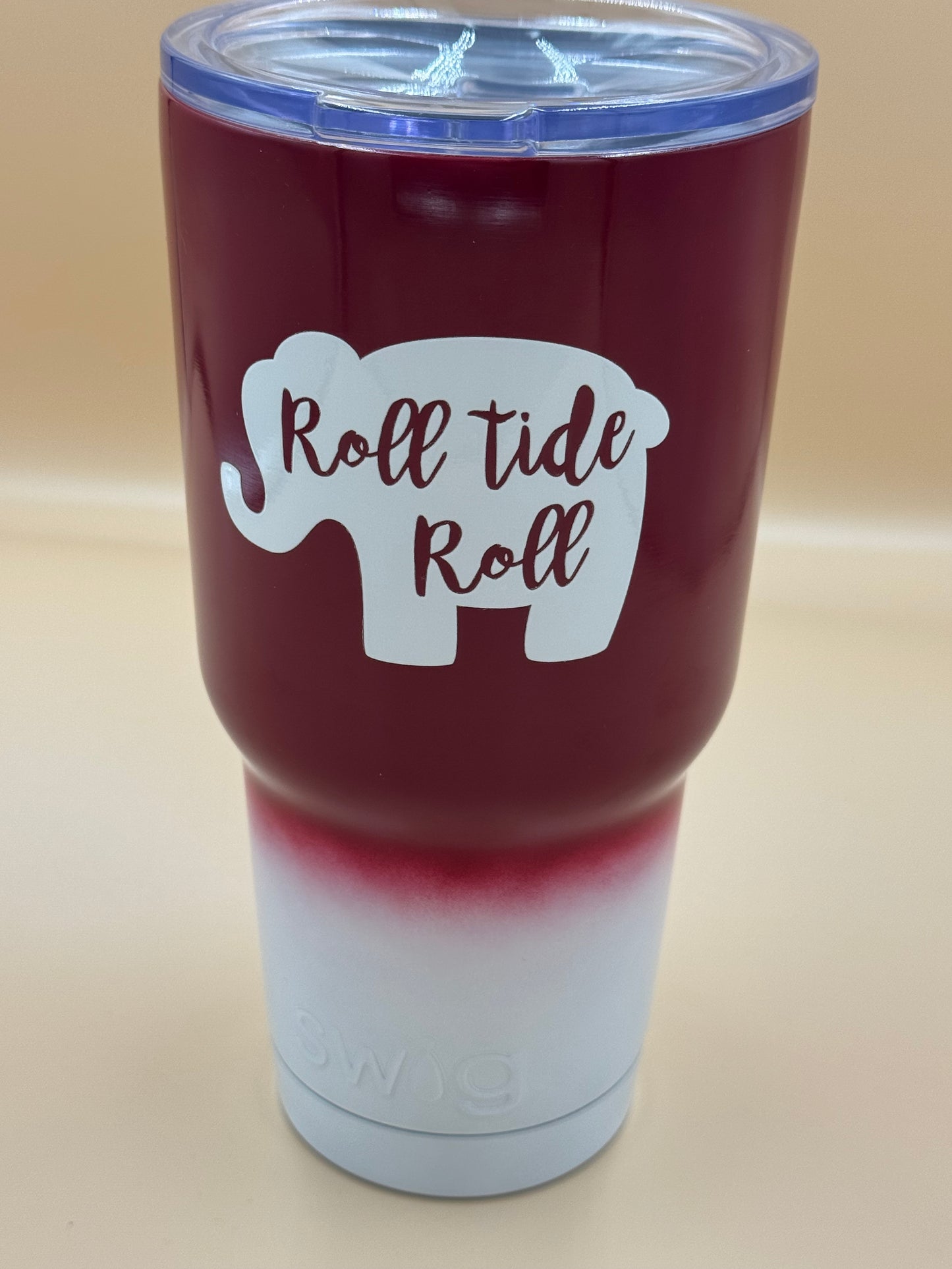 Maroon tumbler with 'Roll Tide Roll' design on a beige background