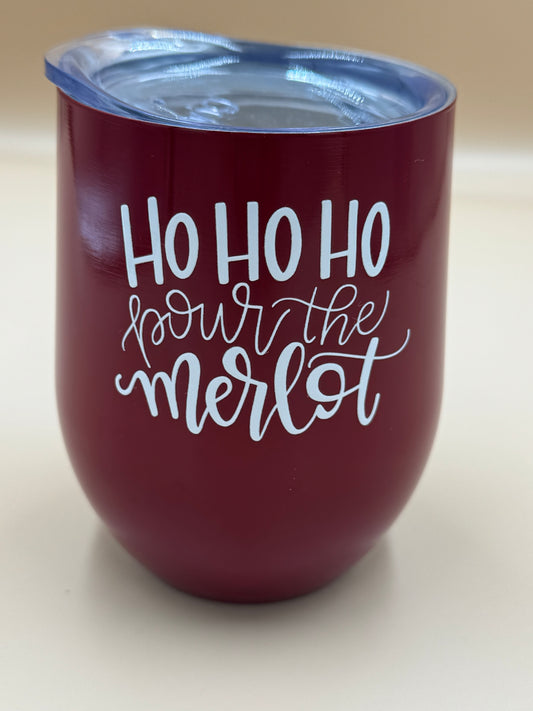 Maroon tumbler with 'Ho Ho Ho pour the merlot' text on a beige background