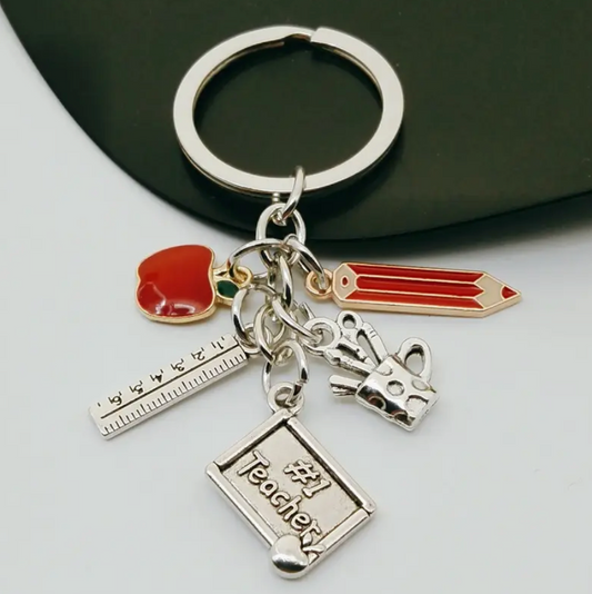 Metal keychain featuring a red pencil and apple, silver ruler, mug with writing utensils, and a plaque that says #1 Teacher—a thoughtful gift for educators.