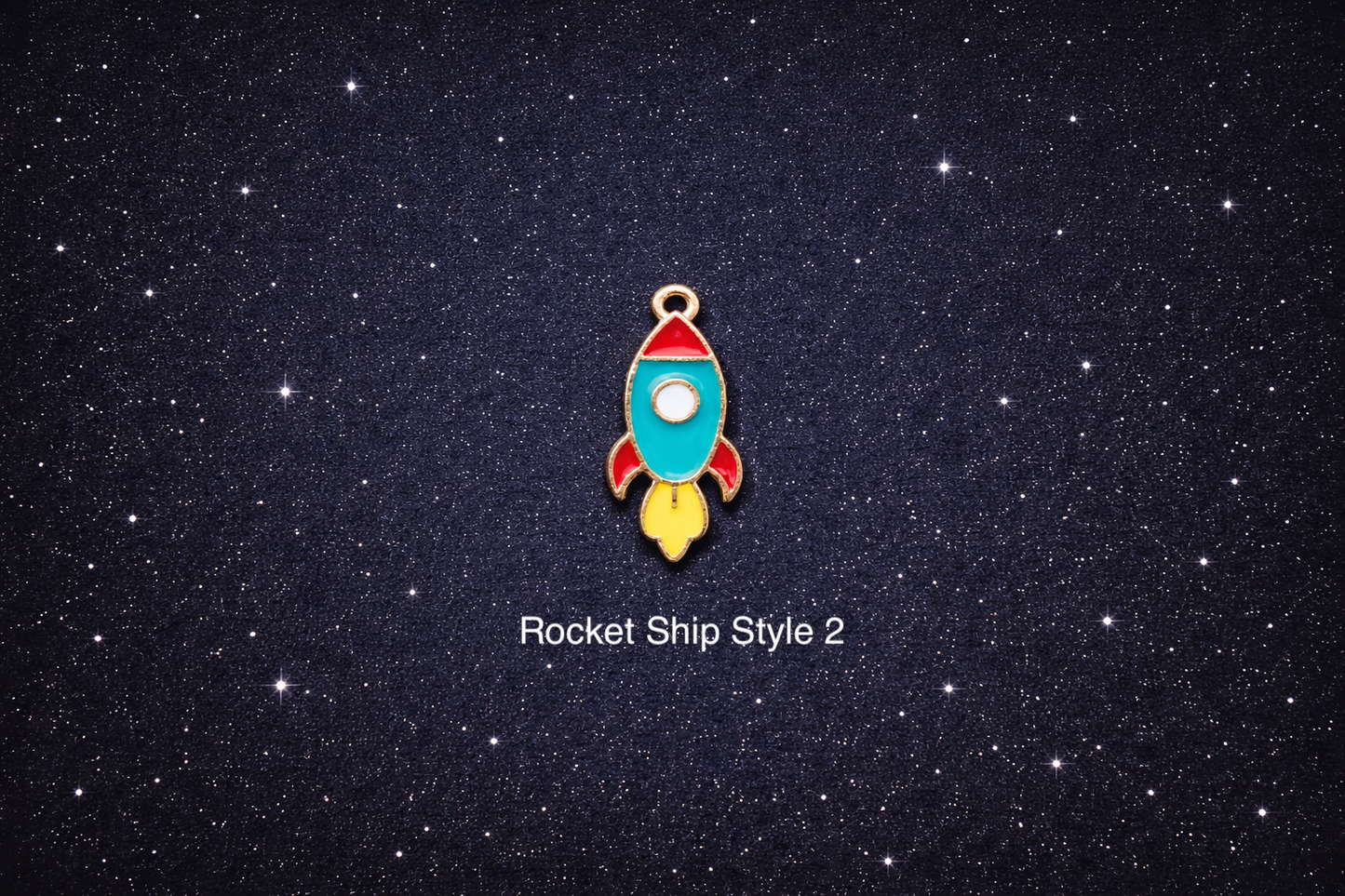 Teal, red, and yellow rocket ship enamel charm with a small top loop, photographed on a dark starry background and sold individually.