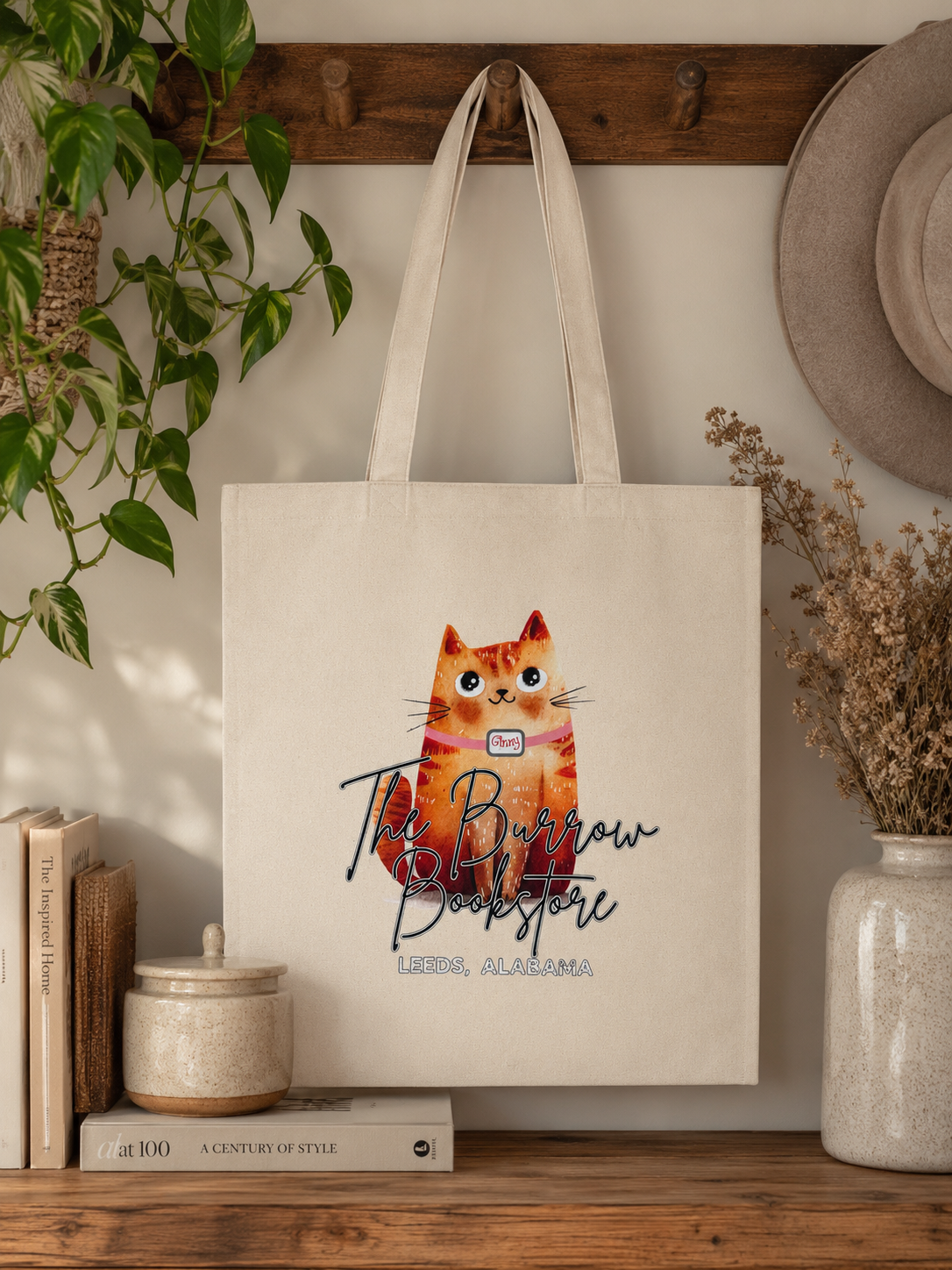 Natural canvas tote bag featuring Ginny, The Burrow Bookstore's orange bookstore cat, with The Burrow Bookstore Leeds, Alabama printed on the front.