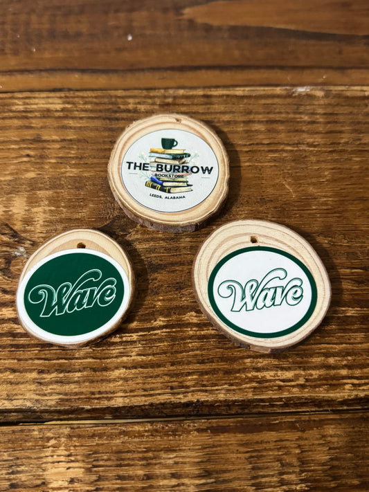 Wooden "coin" with a small drilled hole featuring either the bookstore logo or "Wave" Greenwave mascot design.