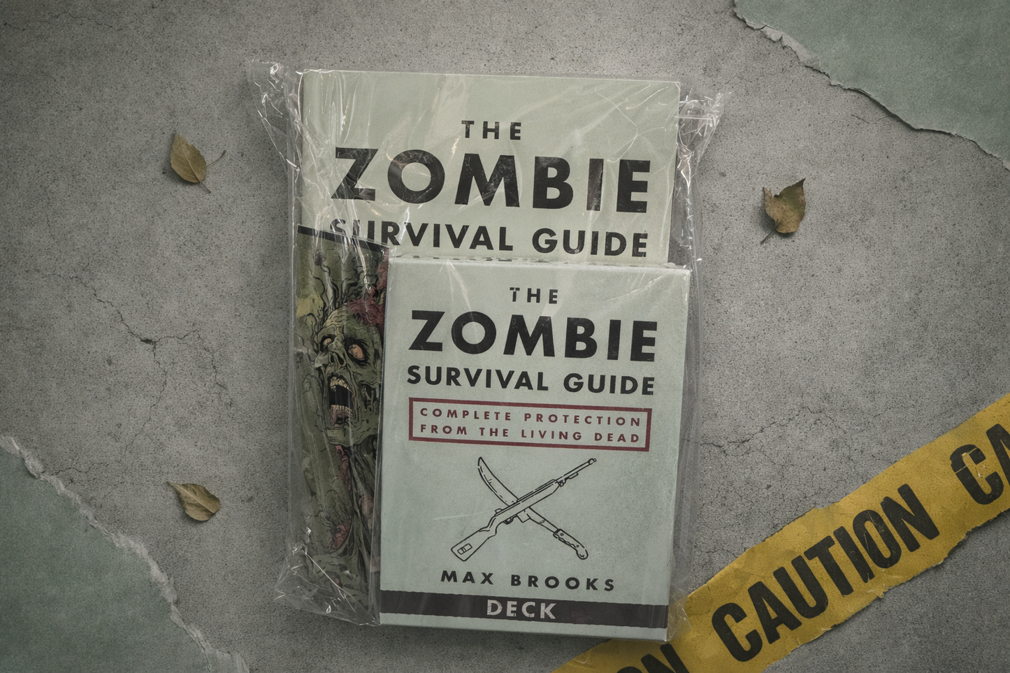 Zombie Survival Guide deck packaging on a textured surface with caution tape.