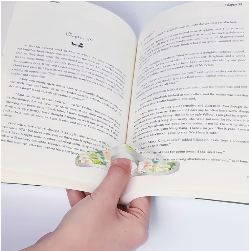 hand using floral acrylic thumb page holder to keep book open while reading