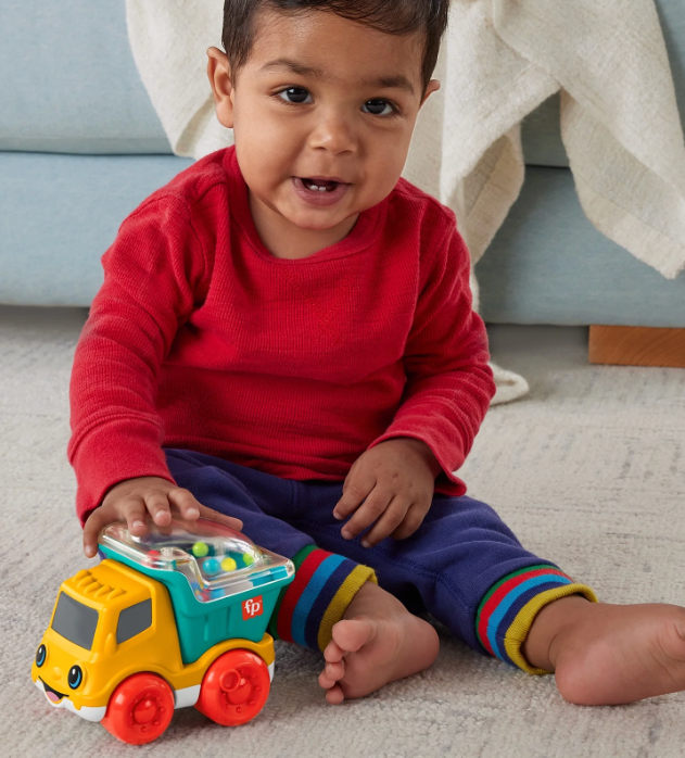 Child playing with a toy truck on a carpeted floor