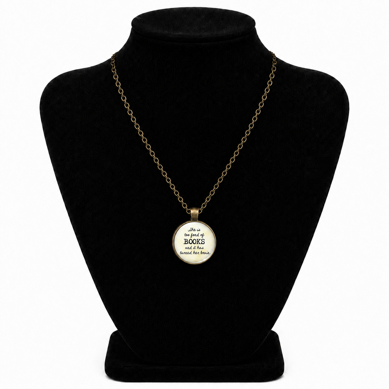 A gold chain necklace with a round pendant displayed on a black velvet jewelry bust. The pendant has a cream-colored center with black text that reads, 'Life is too short to spend on trivial matters, and too short to read without books.