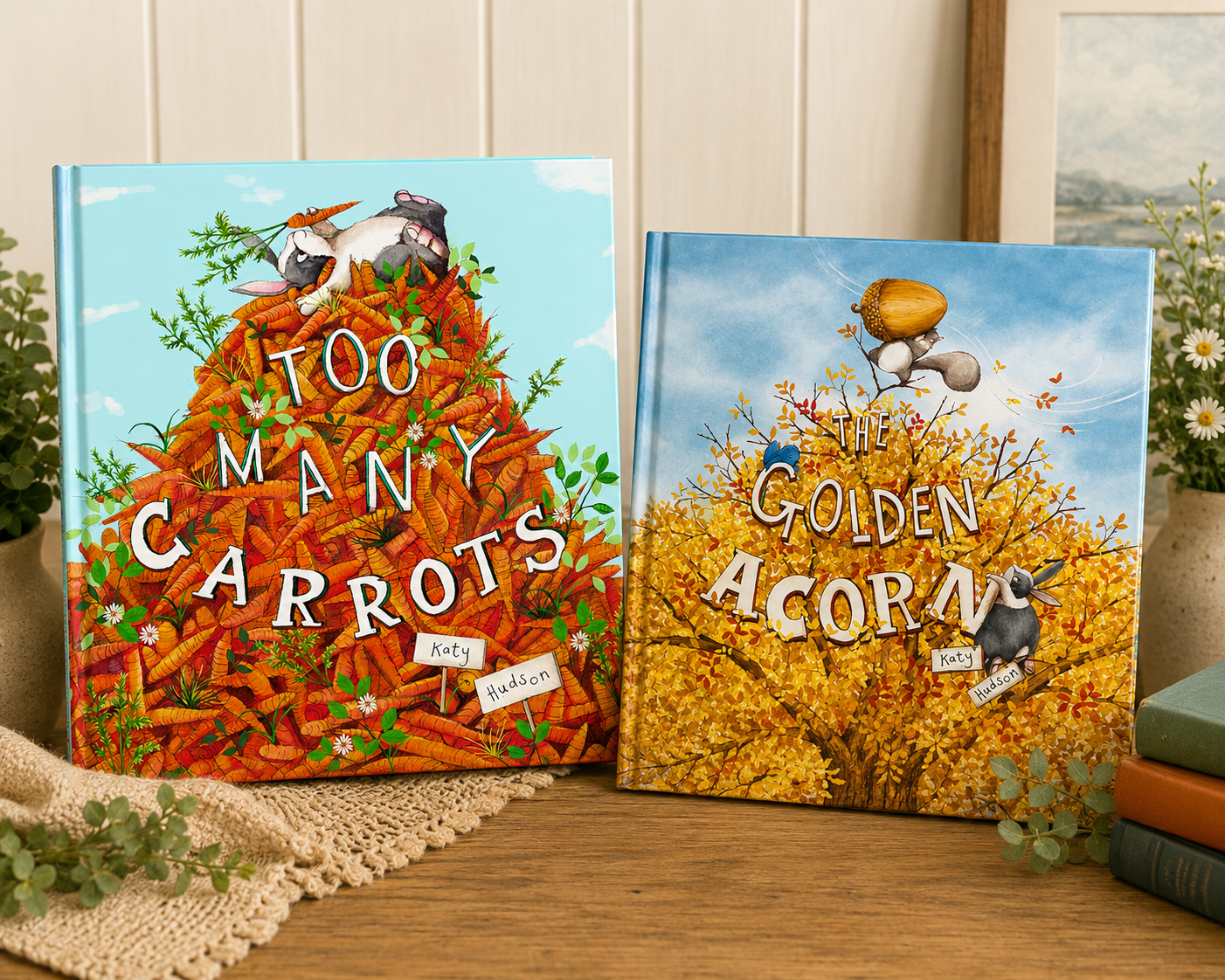 Too Many Carrots and The Golden Acorn by Katy Hudson displayed side by side on a wooden table with greenery, stacked books, and a warm cozy background, highlighting the companion children's picture books.