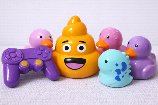 Colorful toy ducks with a central orange duck holding a purple controller on a white background