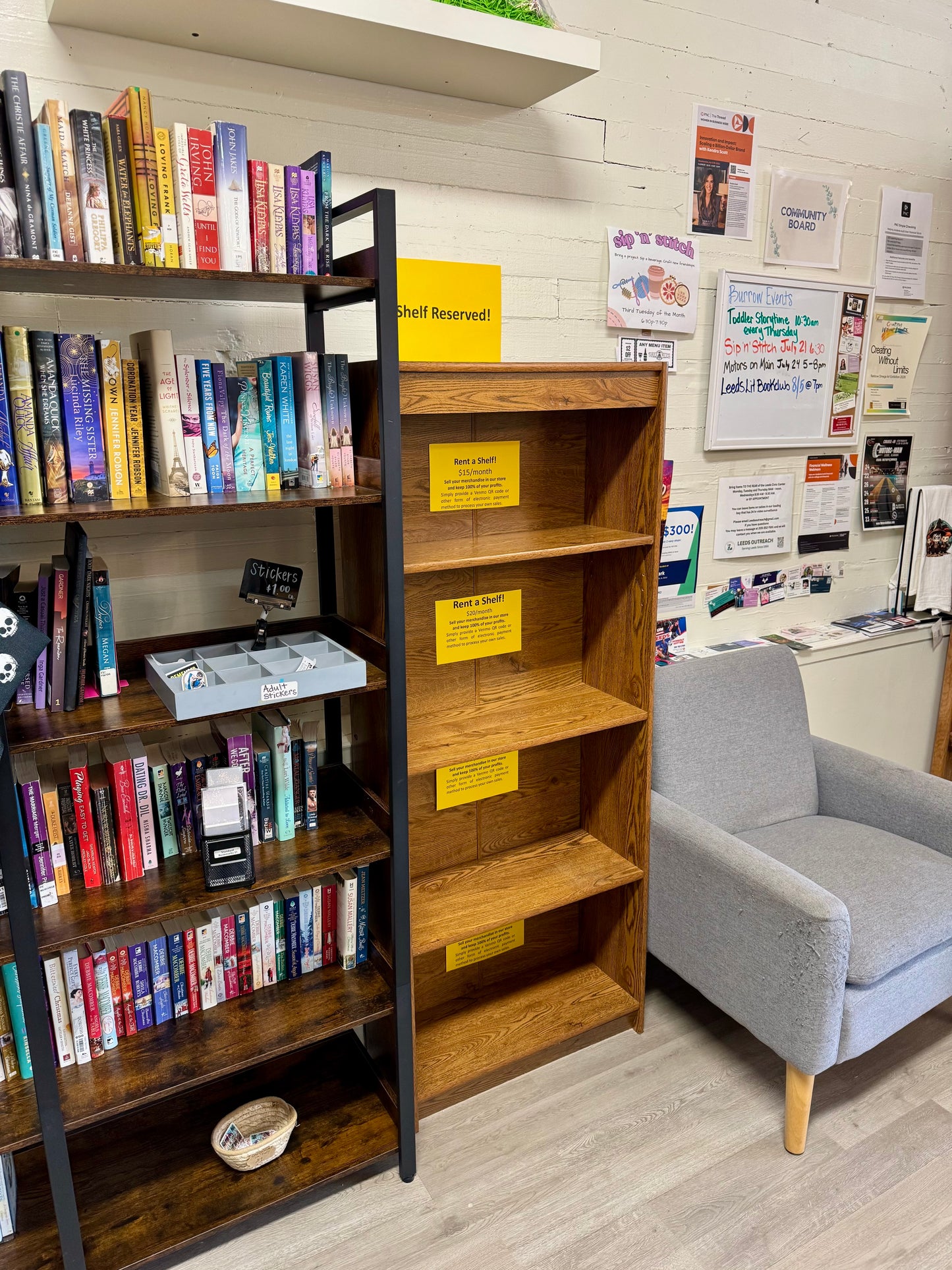 Angled view of wooden vendor display shelving with monthly rental signs in bookstore.