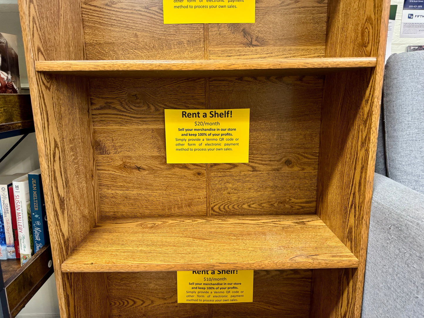 Wooden vendor display shelf with $20 monthly rental sign for local makers and authors.