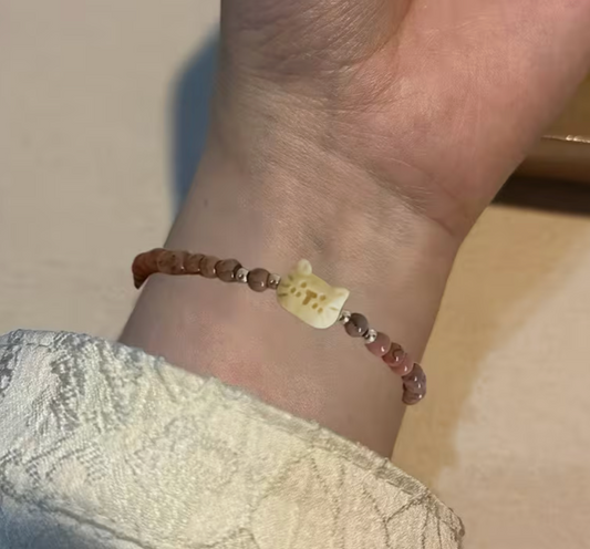 Vintage cat charm beaded bracelet with green and brown beads shown on wrist.