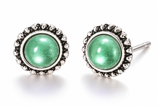Pair of vintage-inspired green cabochon stud earrings featuring glossy shimmering green centers surrounded by ornate antique silver-tone sunburst settings on a white background.