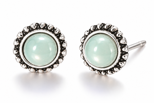 Pair of vintage-inspired light green cabochon stud earrings featuring glossy pastel mint green centers and ornate antique silver-tone sunburst settings on a white background.