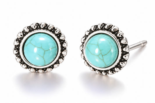 Pair of vintage-inspired turquoise blue cabochon stud earrings with subtle stone-like veining and ornate antique silver-tone sunburst settings displayed on a white background.