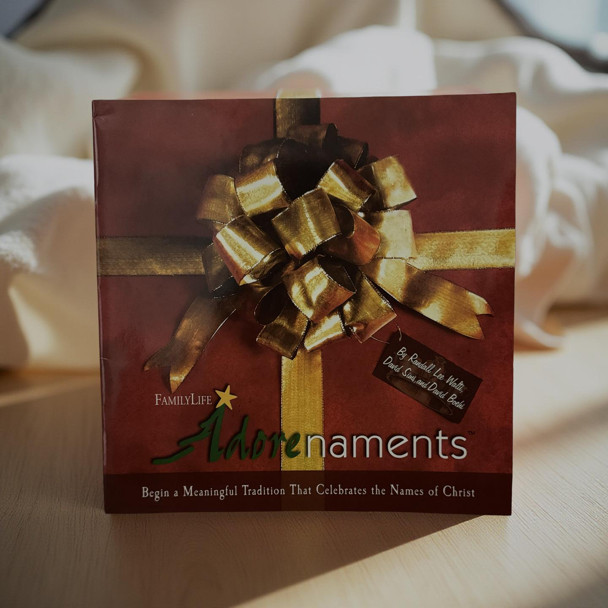 Front cover or boxed set of Adorenaments by FamilyLife shown on a Christmas background, Christ centered holiday devotional with ornaments