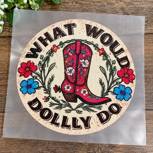What Would Dolly Do 2.75-inch heat transfer decal featuring a vintage pink floral cowboy boot surrounded by red and blue wildflowers, greenery, and distressed western lettering on clear carrier film.
