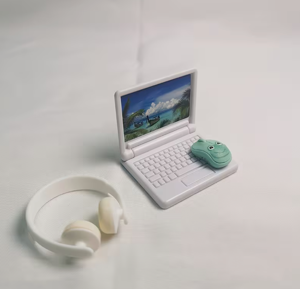 White miniature laptop with headphones and small mouse