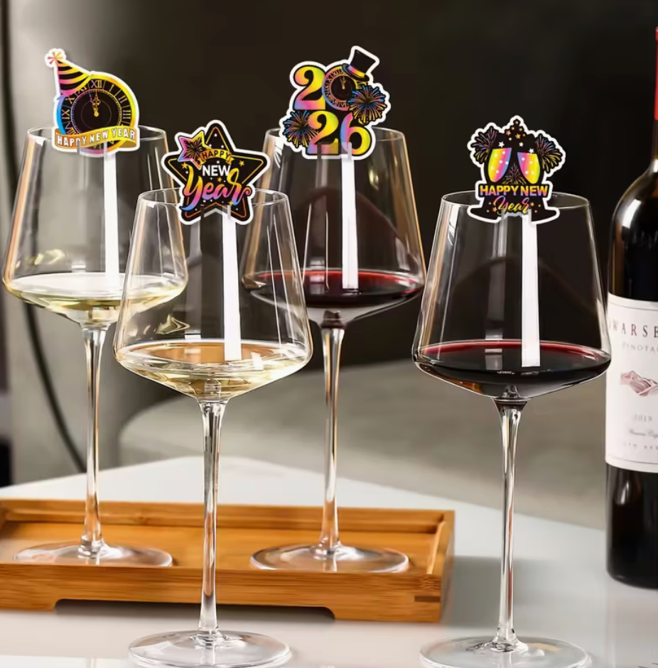 wine glasses filled with white and red wine decorated with colorful new year 2026 stem markers