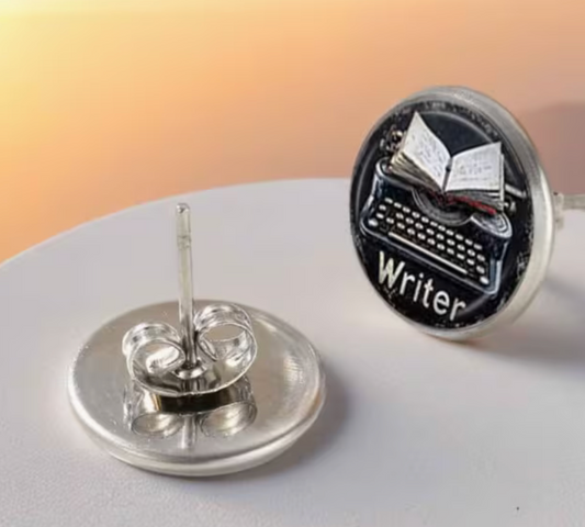 Round silver-tone Writer stud earrings featuring a vintage typewriter with an open book above it on a black background, with butterfly-style earring backs.