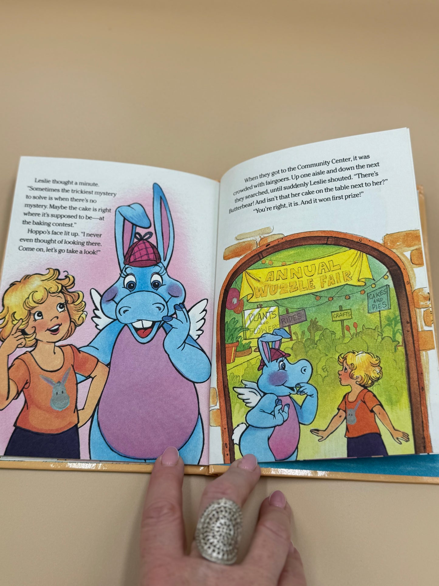 Open book with cartoon characters and a hand holding it