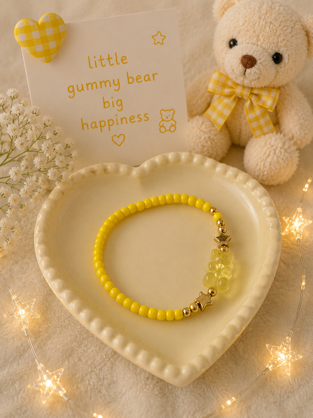 Yellow stretch bead bracelet with transparent gummy bear charm and gold accents displayed with soft pastel decor