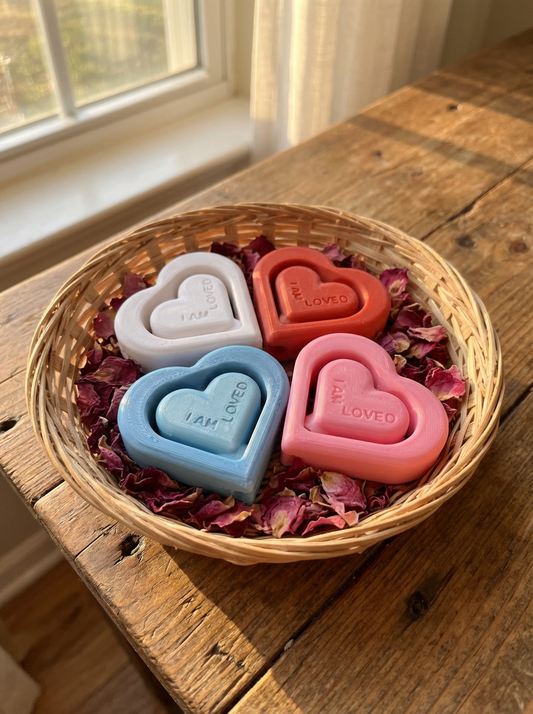 Heart-shaped spinning pencil toppers that say You Are Loved displayed in a basket with dried rose petals on a wooden table